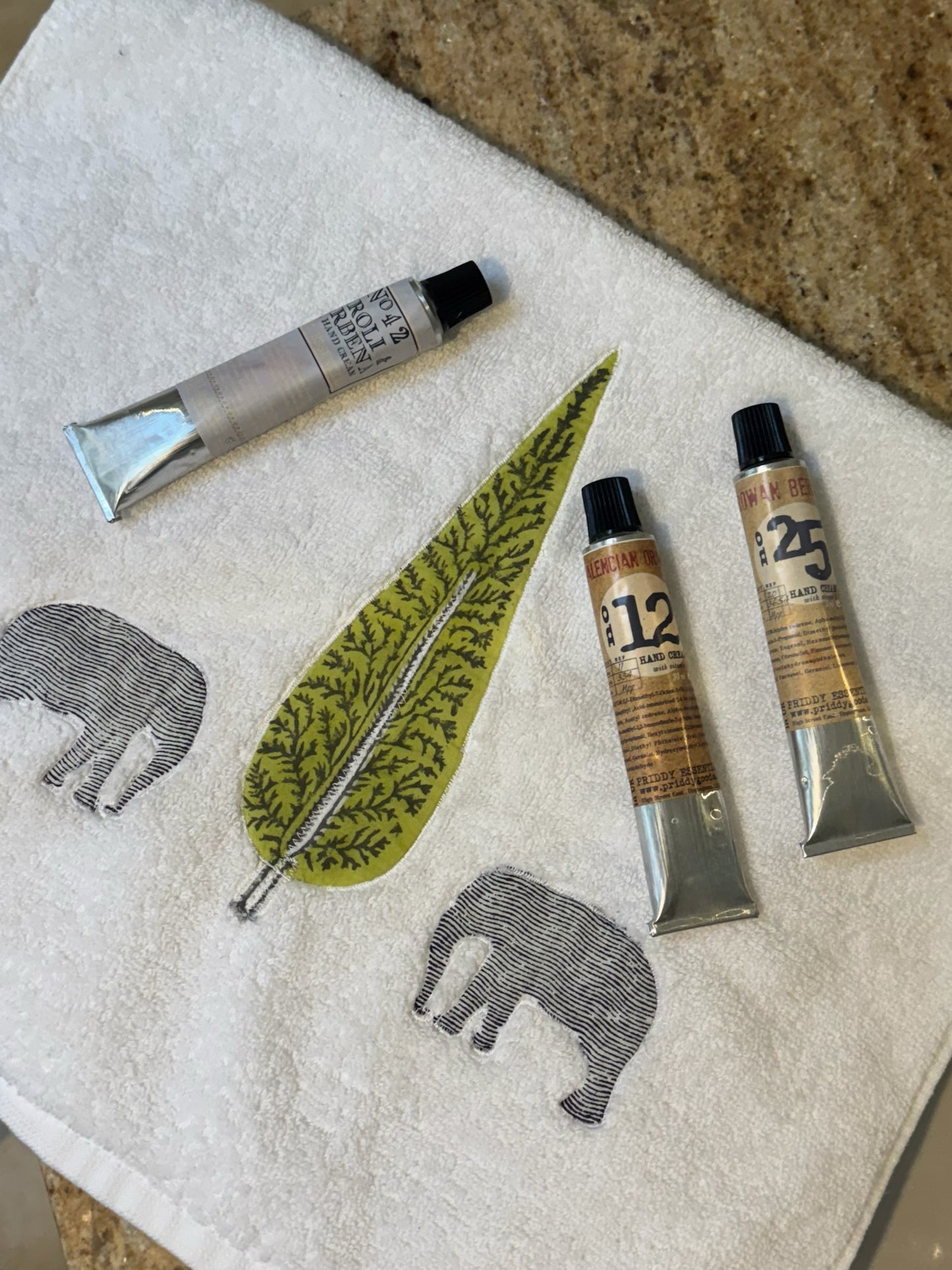 Three tubes of paint on a towel with elephant and leaf designs