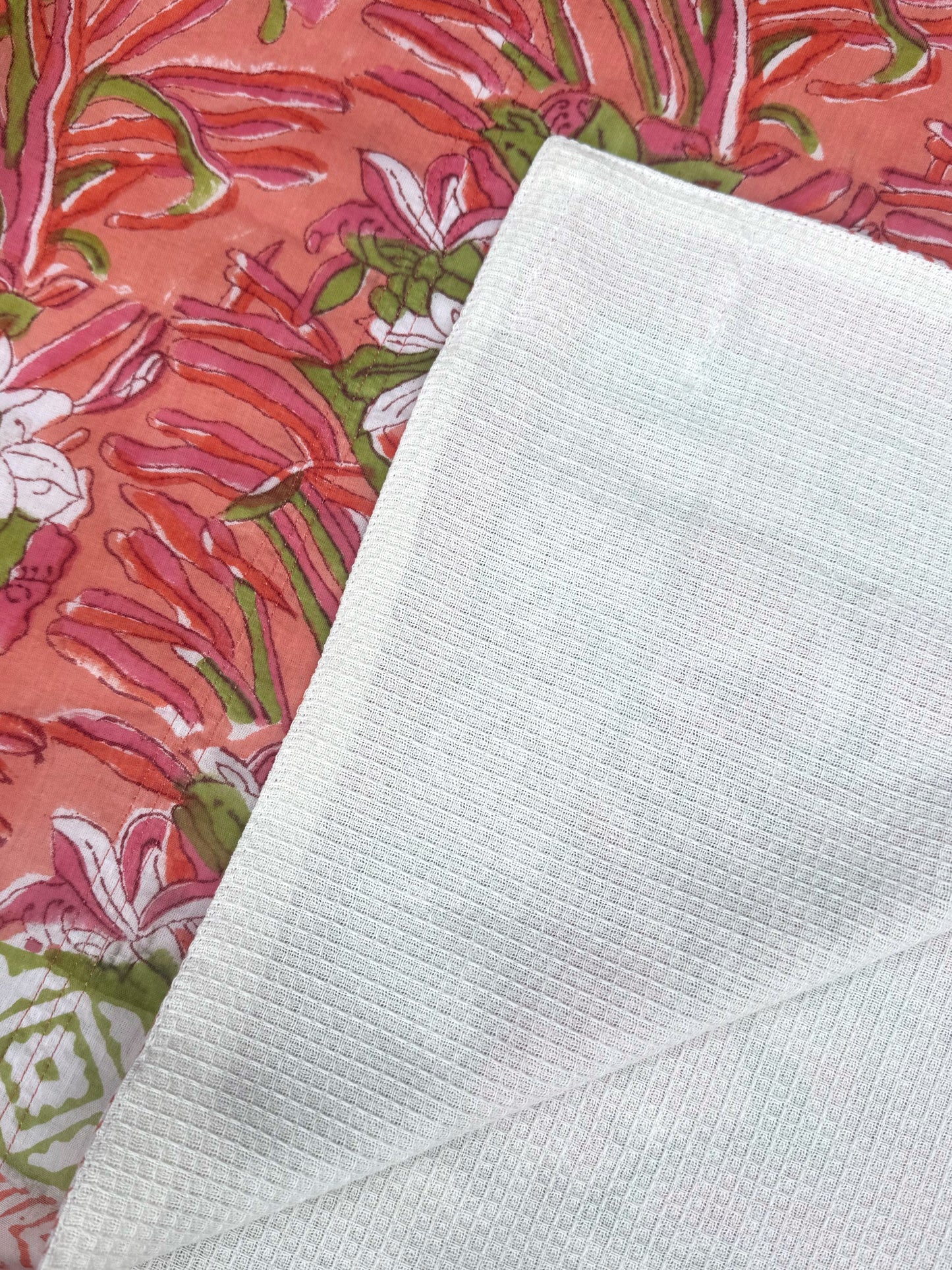 Close-up of a textured white fabric next to a colorful floral patterned fabric.