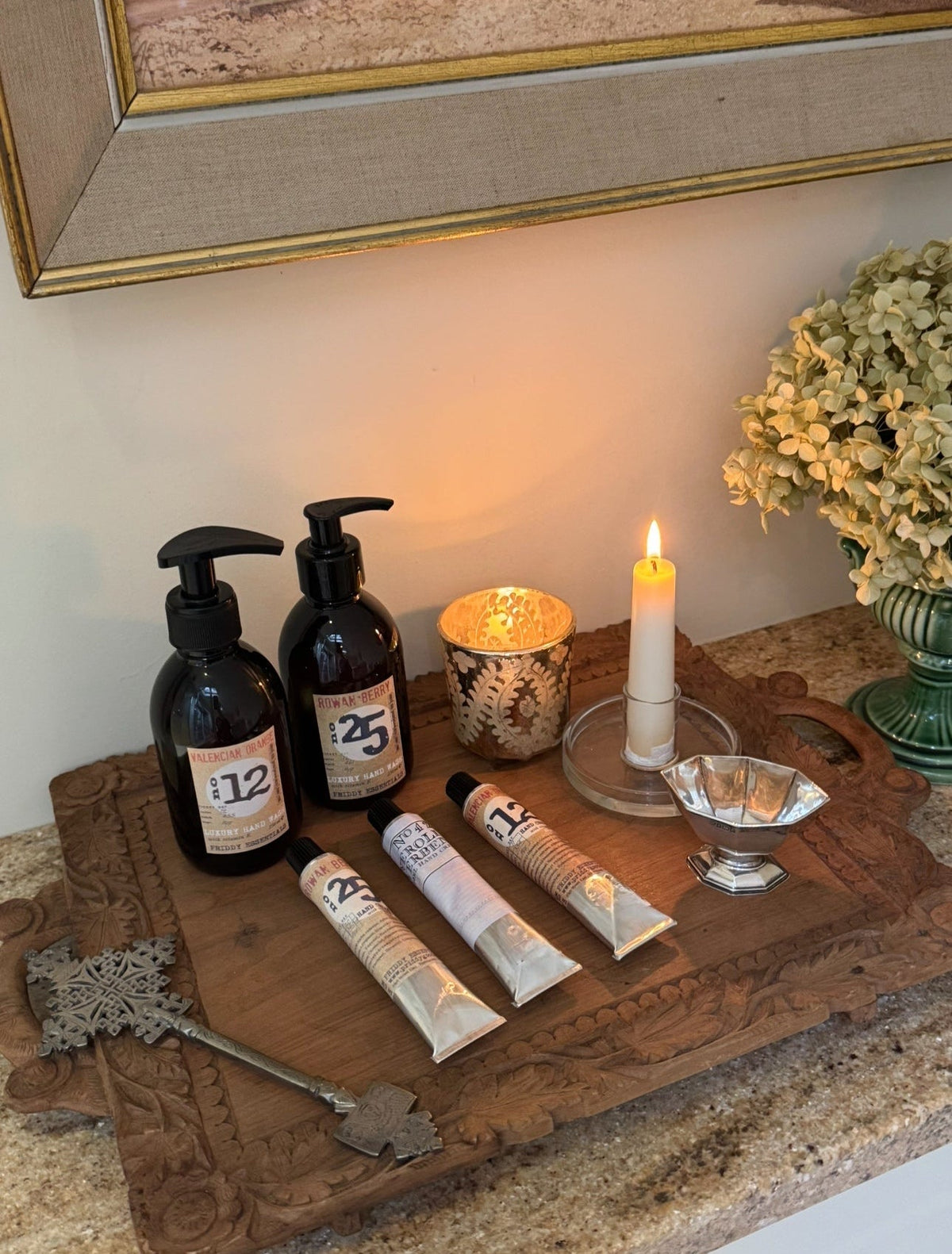 Decorative setup with bottles, candles, and a key on a wooden surface.