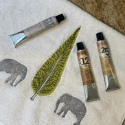 Three tubes of paint on a towel with elephant and leaf designs