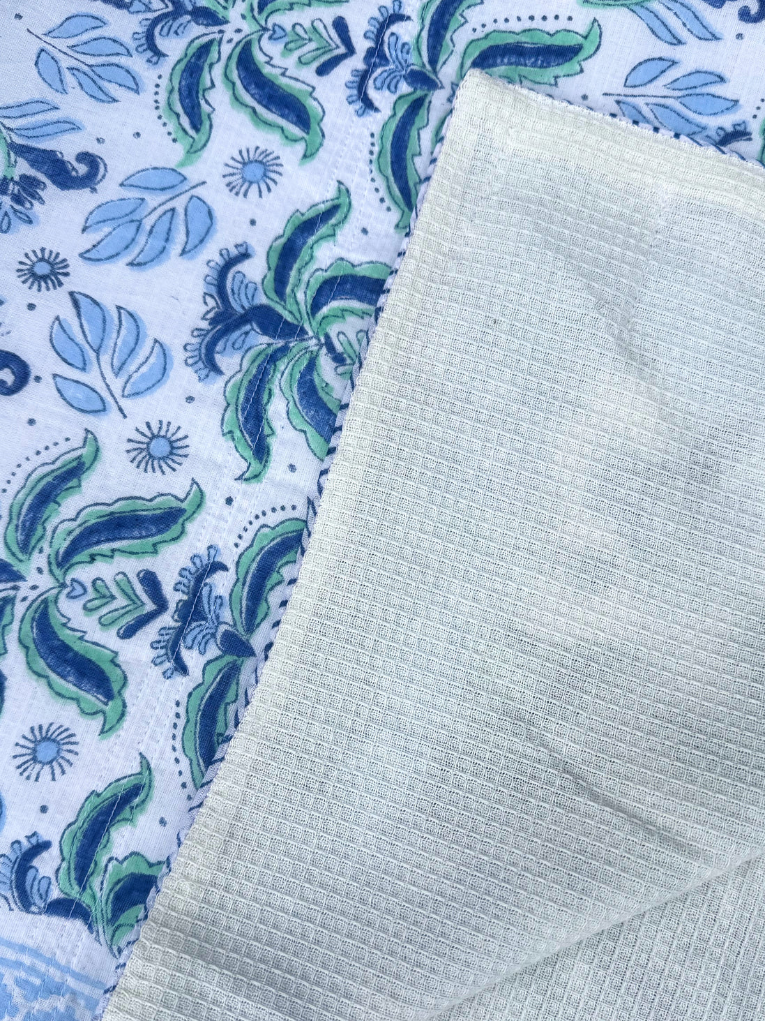 Textured light green fabric on a patterned blue and white background