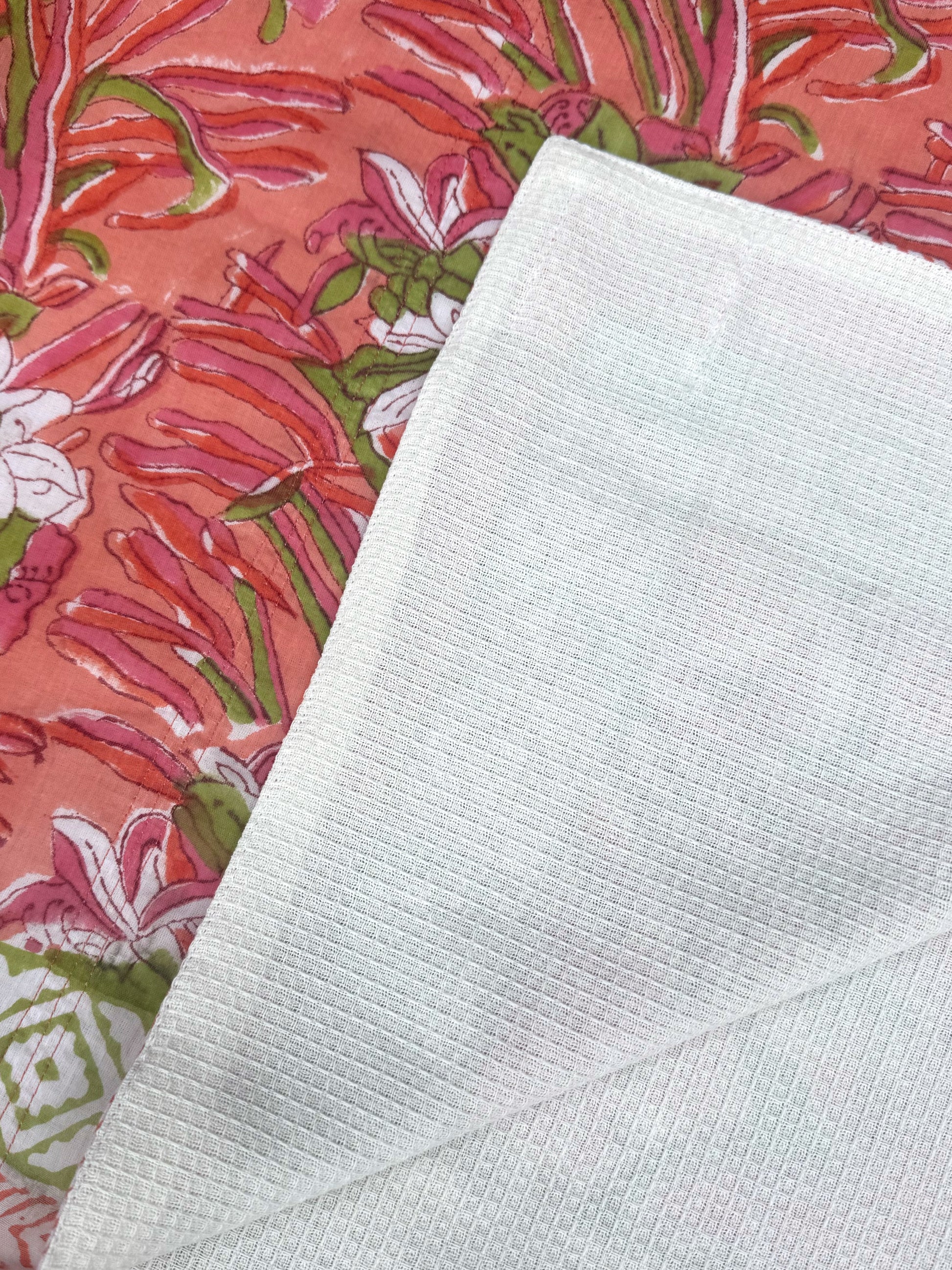 Close-up of a textured white fabric next to a colorful floral patterned fabric.